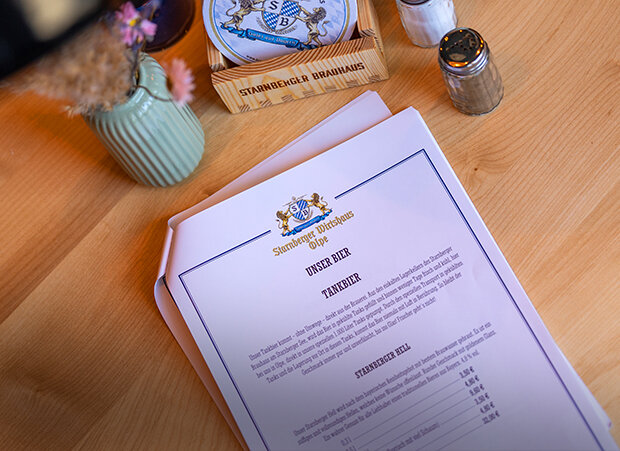 Getränkekarte auf weißem Papier liegt auf einem Holztisch.